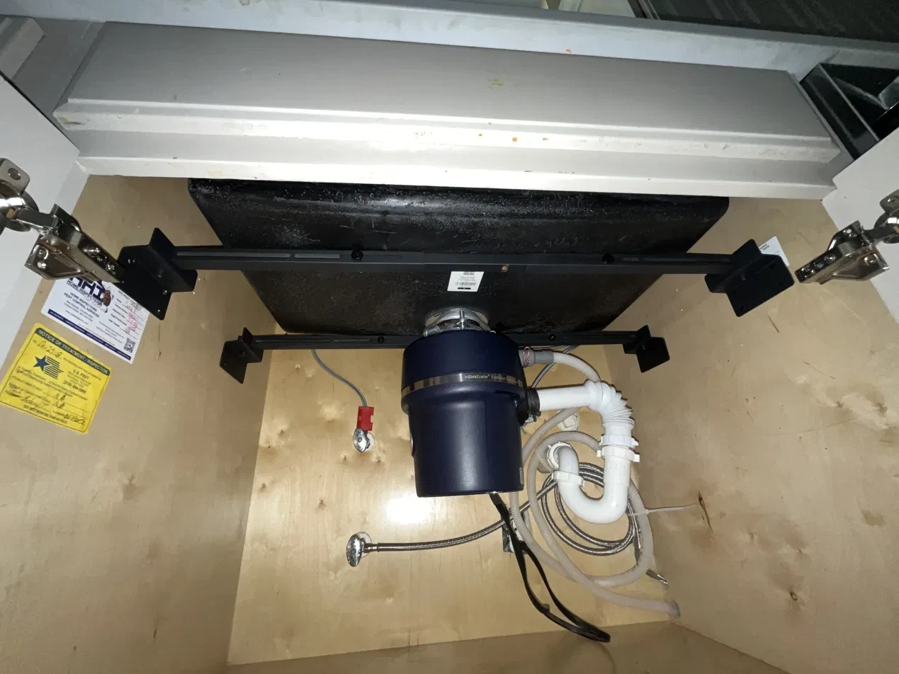 Garbage disposal and plumbing installed under a kitchen sink